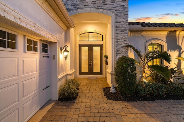 exterior entry at dusk with a garage and french doors