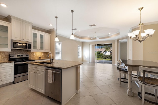 kitchen featuring appliances with stainless steel finishes, decorative light fixtures, sink, and a tray ceiling