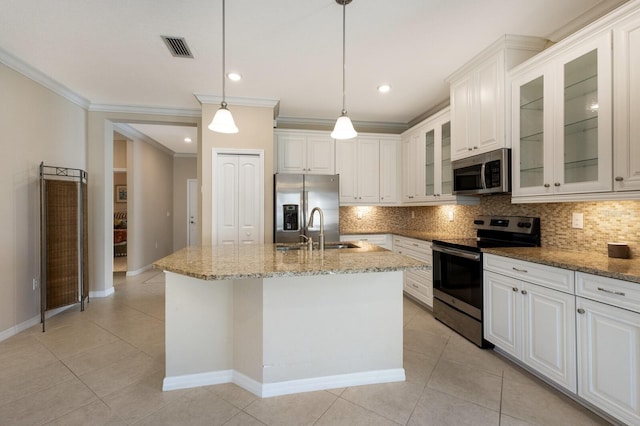 kitchen with appliances with stainless steel finishes, decorative light fixtures, white cabinetry, an island with sink, and sink