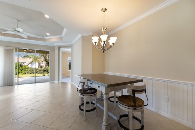 tiled dining space with a tray ceiling, crown molding, and ceiling fan with notable chandelier