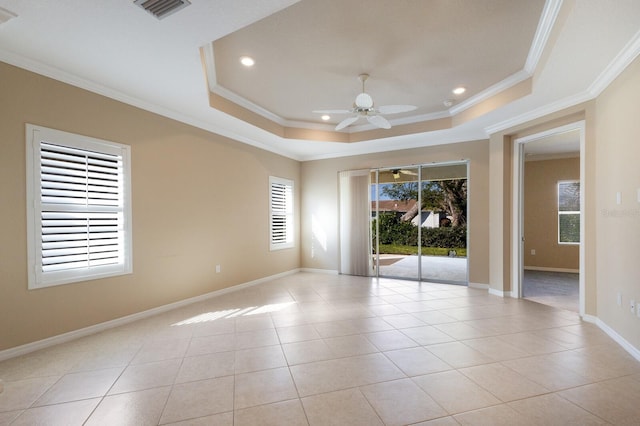 empty room featuring crown molding, ceiling fan, a tray ceiling, and light tile patterned floors