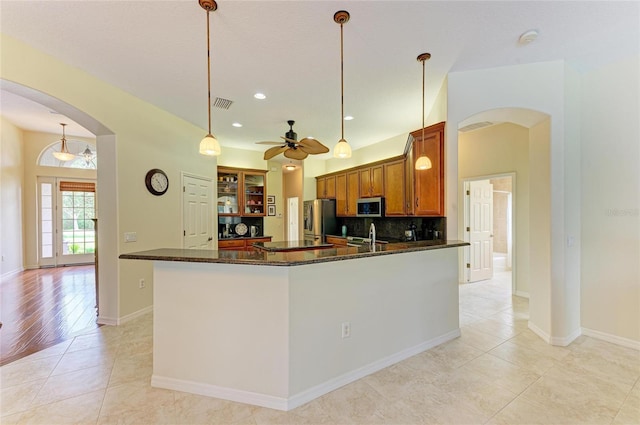 kitchen with pendant lighting, light tile patterned floors, dark stone countertops, stainless steel appliances, and decorative backsplash