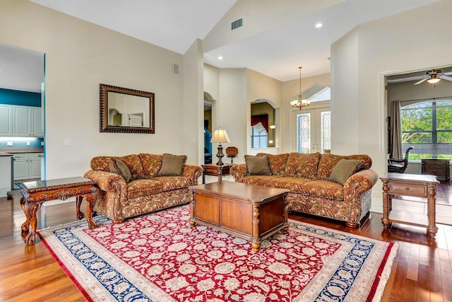 living room featuring high vaulted ceiling, a chandelier, and hardwood / wood-style floors