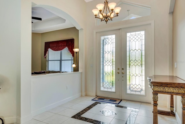 tiled foyer with french doors and an inviting chandelier