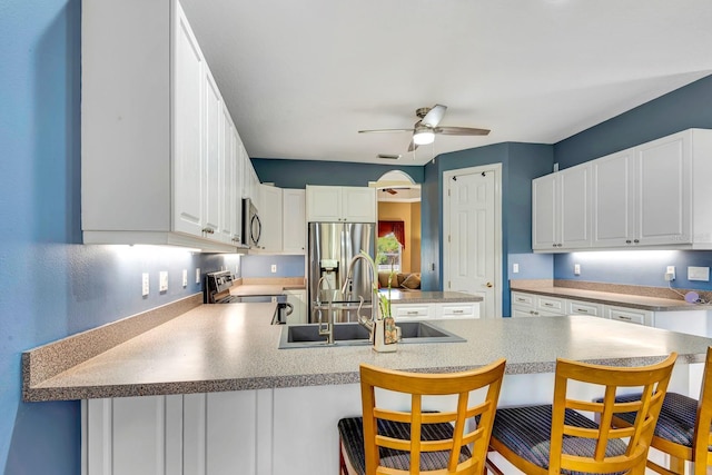 kitchen featuring sink, a breakfast bar area, appliances with stainless steel finishes, white cabinetry, and kitchen peninsula