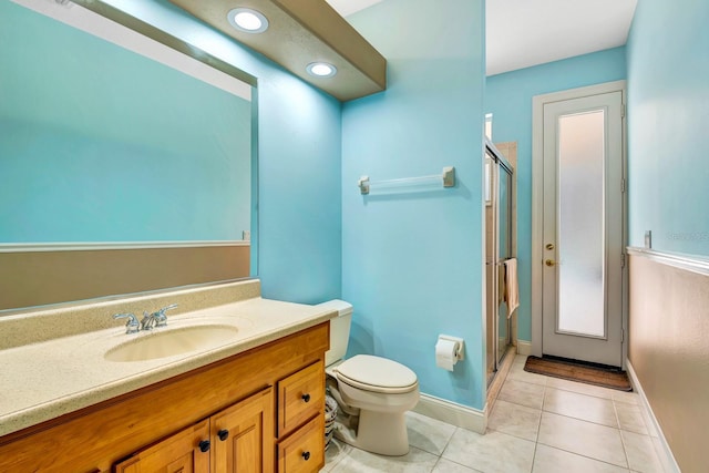 bathroom featuring a shower with door, vanity, tile patterned floors, and toilet