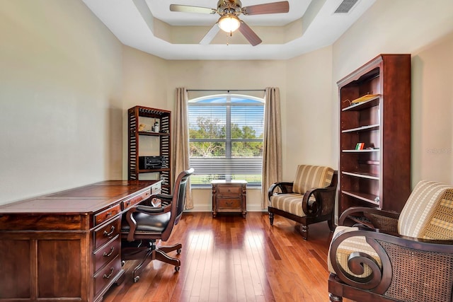 office space with hardwood / wood-style floors, a raised ceiling, and ceiling fan