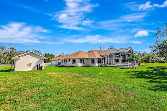 rear view of property with glass enclosure and a lawn