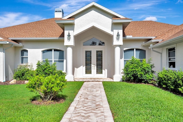 5750 Saddle Oak Trl, Sarasota, FL 34241 - view of exterior entry featuring french doors, a yard, roof with shingles, and stucco siding