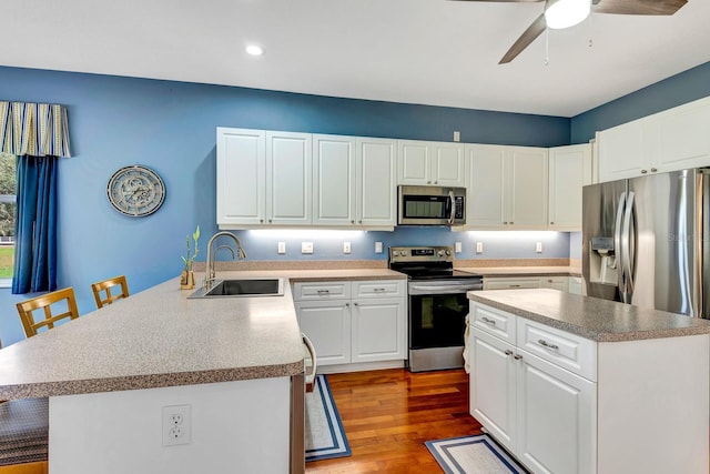 5750 Saddle Oak Trl, Sarasota, FL 34241 - kitchen featuring appliances with stainless steel finishes, a peninsula, wood finished floors, ceiling fan, and a center island