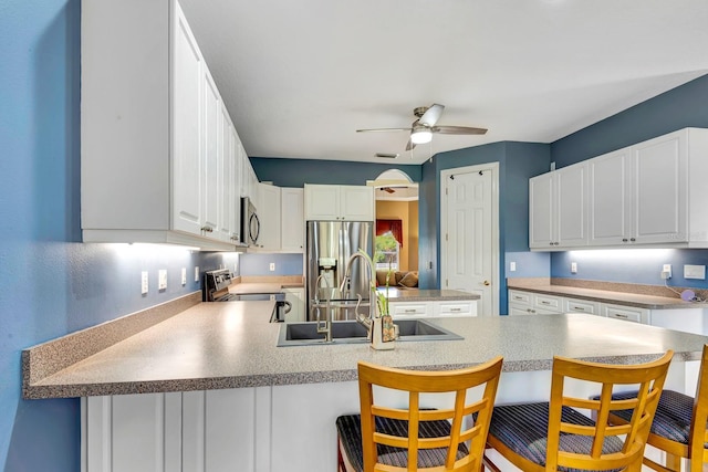5750 Saddle Oak Trl, Sarasota, FL 34241 - kitchen featuring appliances with stainless steel finishes, a peninsula, ceiling fan, white cabinets, and a breakfast bar