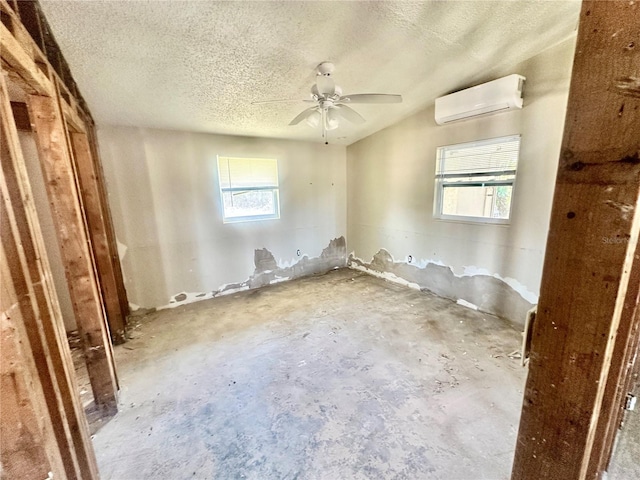 empty room with ceiling fan, an AC wall unit, and a textured ceiling