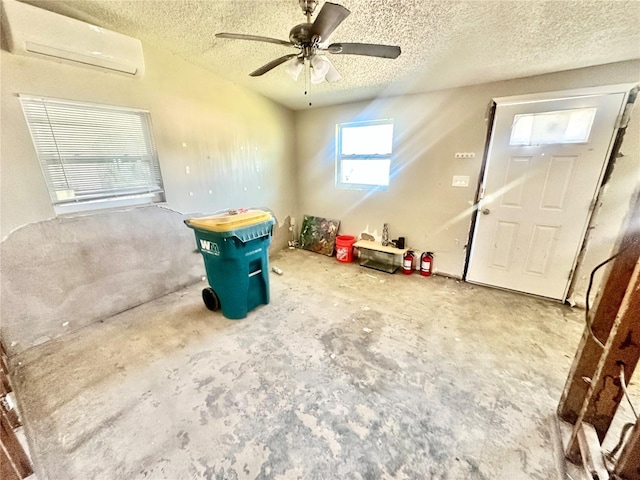 recreation room featuring ceiling fan, a wall unit AC, concrete floors, and a textured ceiling