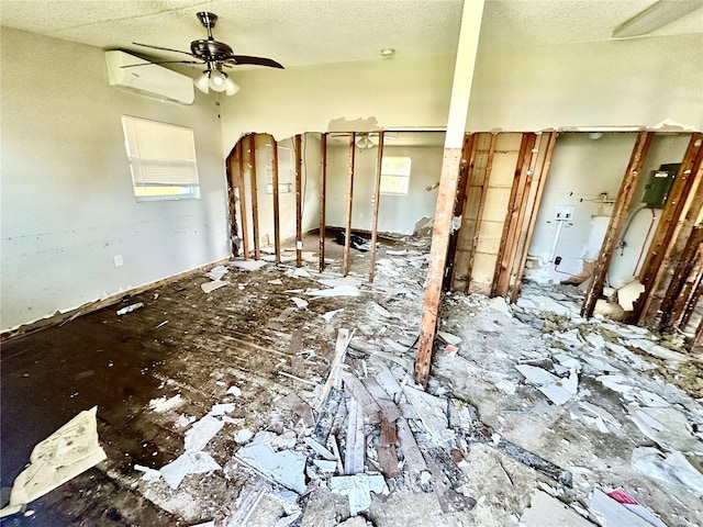 empty room featuring ceiling fan, a wall unit AC, and a textured ceiling