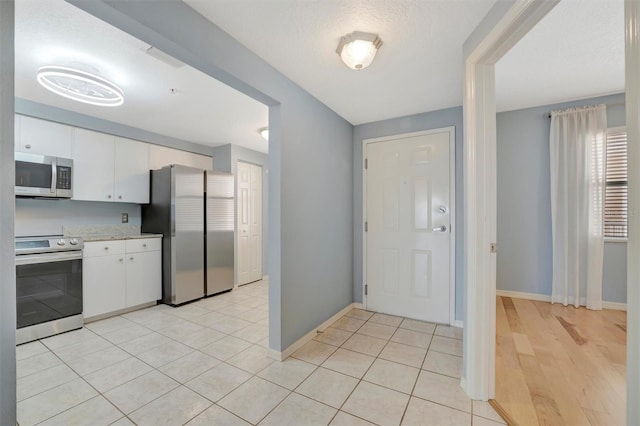 kitchen featuring stainless steel appliances, white cabinets, light countertops, and light tile patterned floors