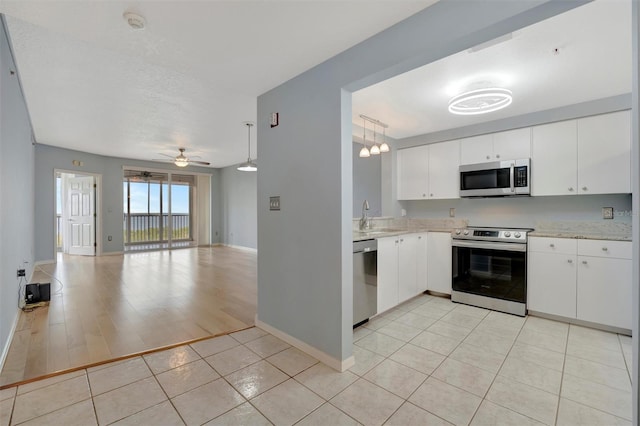 kitchen featuring decorative light fixtures, stainless steel appliances, light countertops, open floor plan, and white cabinets