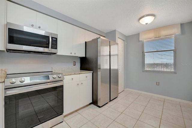 kitchen featuring light tile patterned floors, baseboards, white cabinets, stainless steel appliances, and a textured ceiling