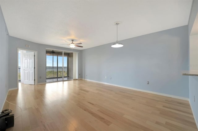 unfurnished living room featuring light wood-type flooring, a ceiling fan, and baseboards