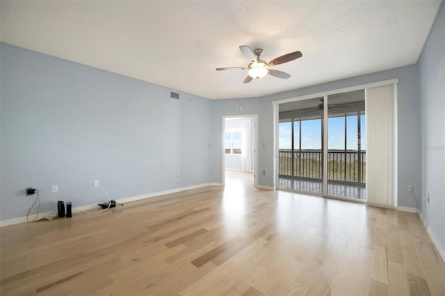 empty room with ceiling fan, light wood-type flooring, visible vents, and baseboards