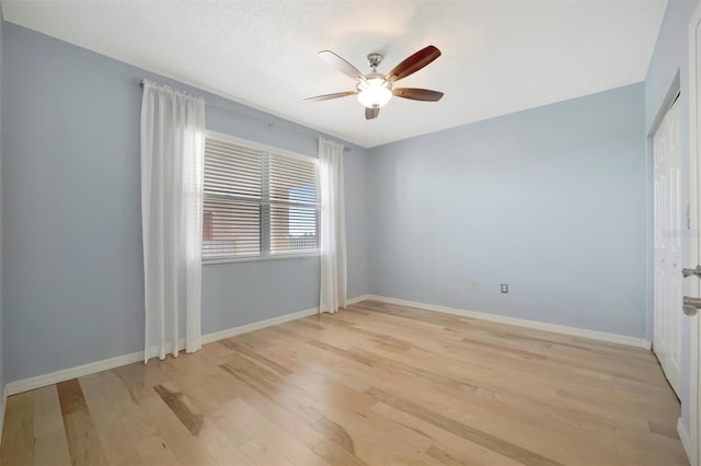 empty room featuring a ceiling fan, light wood-type flooring, a textured ceiling, and baseboards