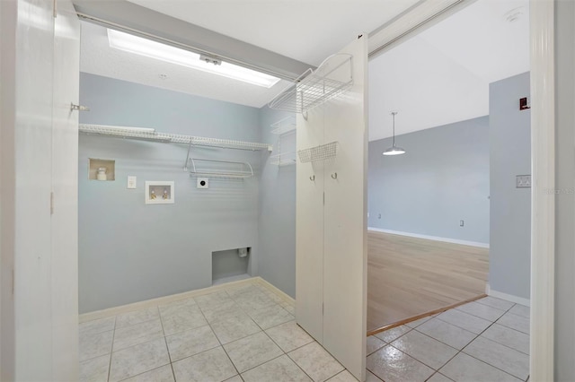 washroom with light tile patterned floors, washer hookup, baseboards, and hookup for an electric dryer