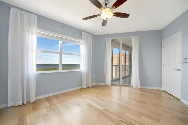 spare room with a ceiling fan, plenty of natural light, light wood-style flooring, and baseboards