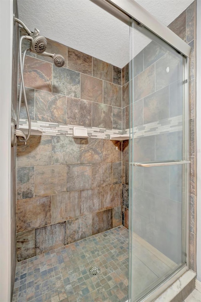 full bath with a textured ceiling and a shower stall