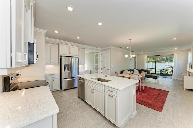 kitchen featuring sink, appliances with stainless steel finishes, pendant lighting, light stone countertops, and a kitchen island with sink