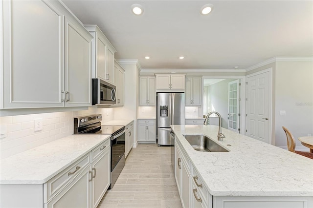 kitchen featuring white cabinets, appliances with stainless steel finishes, sink, and a kitchen island with sink