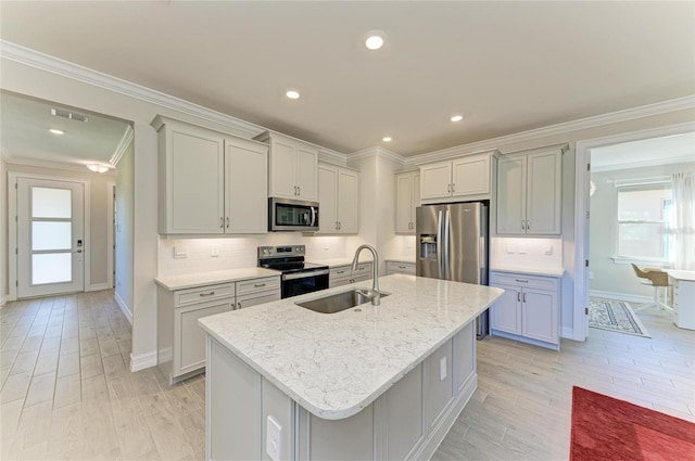 kitchen featuring sink, light stone counters, crown molding, stainless steel appliances, and a kitchen island with sink