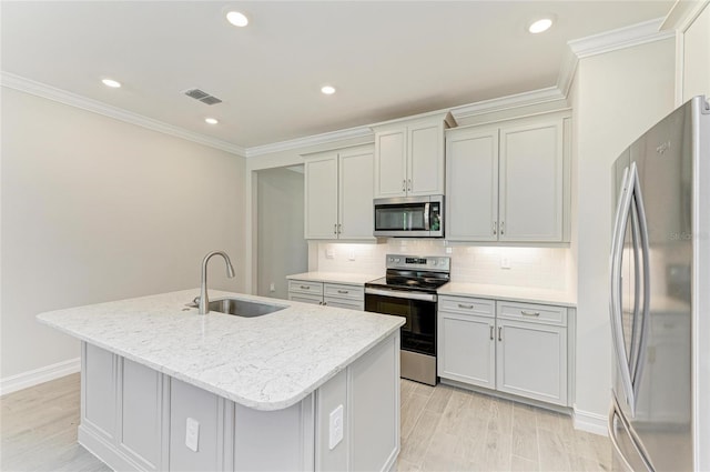 kitchen with sink, light stone counters, appliances with stainless steel finishes, an island with sink, and backsplash