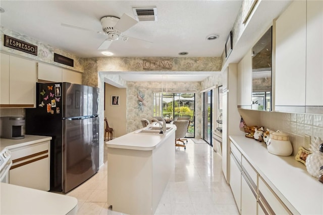 534 Warwick Ln, Venice, FL 34293 - kitchen with visible vents, light countertops, freestanding refrigerator, decorative backsplash, and wallpapered walls