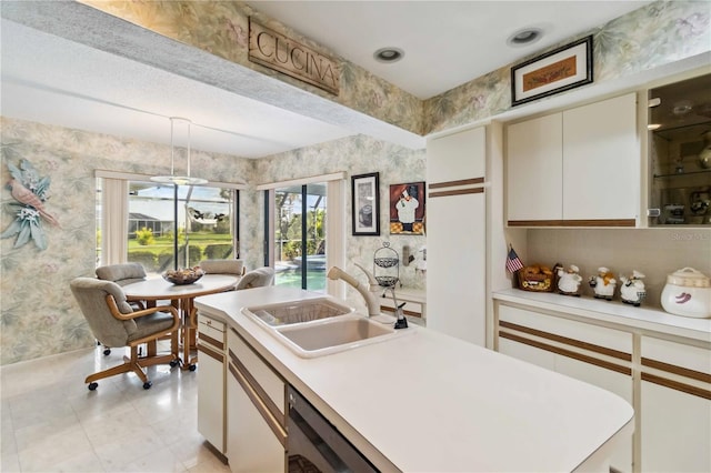 534 Warwick Ln, Venice, FL 34293 - kitchen with light countertops, a sink, decorative light fixtures, and wallpapered walls