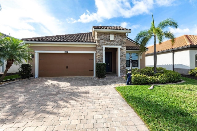 mediterranean / spanish-style house with decorative driveway, stucco siding, an attached garage, stone siding, and a tiled roof