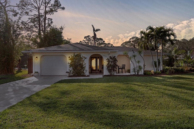 ranch-style home featuring a garage and a lawn