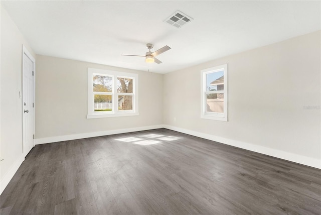 spare room featuring baseboards, visible vents, dark wood-style flooring, and ceiling fan