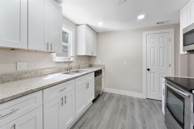 kitchen featuring a sink, light stone counters, visible vents, appliances with stainless steel finishes, and white cabinets