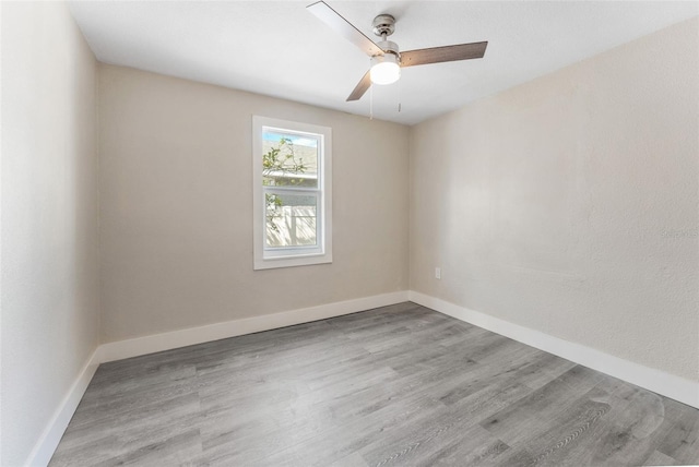 spare room with baseboards, ceiling fan, and light wood finished floors