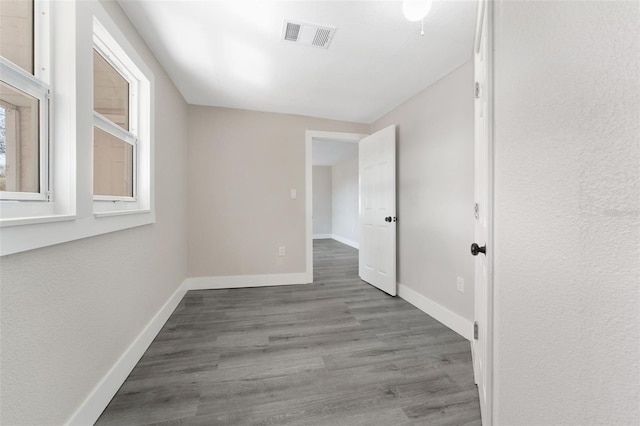 spare room featuring baseboards, visible vents, and wood finished floors