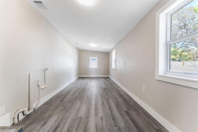 empty room featuring baseboards, visible vents, and dark wood-style flooring