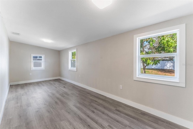empty room featuring baseboards, wood finished floors, and visible vents