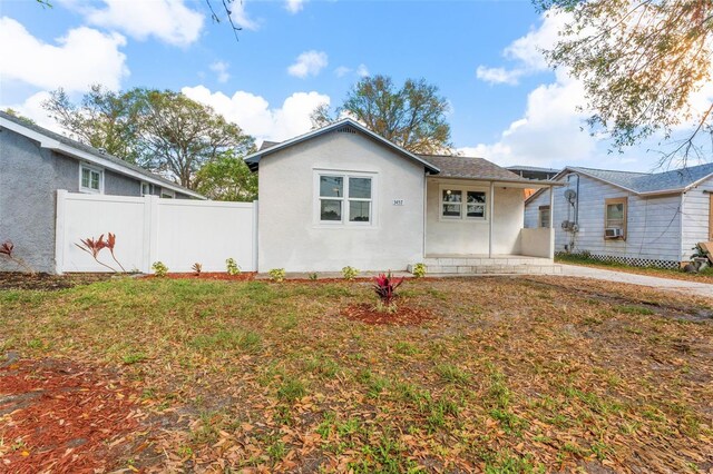view of front of home with stucco siding, cooling unit, fence, a patio, and a front yard