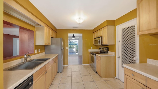 kitchen featuring appliances with stainless steel finishes, light brown cabinetry, sink, light tile patterned floors, and ceiling fan