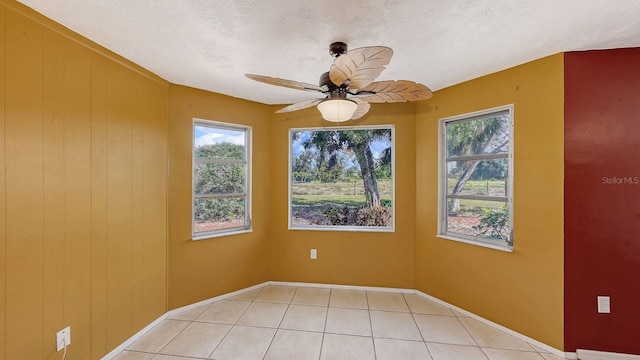 tiled empty room with a healthy amount of sunlight, a textured ceiling, and ceiling fan