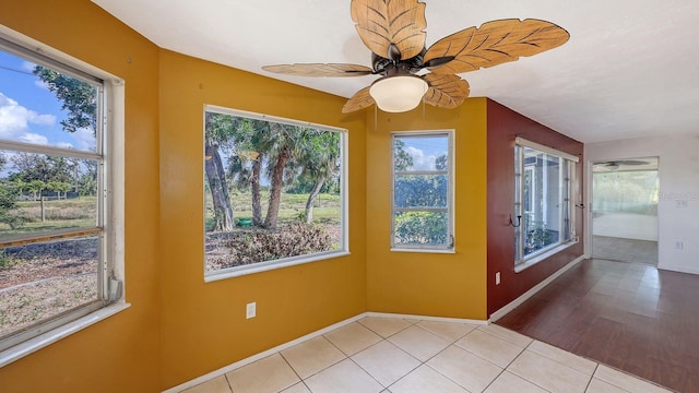 tiled empty room with a healthy amount of sunlight and ceiling fan