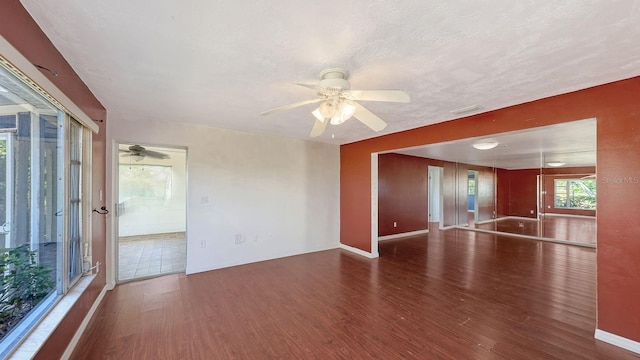 unfurnished living room featuring a textured ceiling, dark wood-type flooring, and ceiling fan