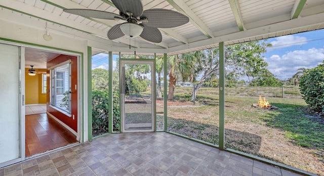 unfurnished sunroom featuring ceiling fan and beam ceiling