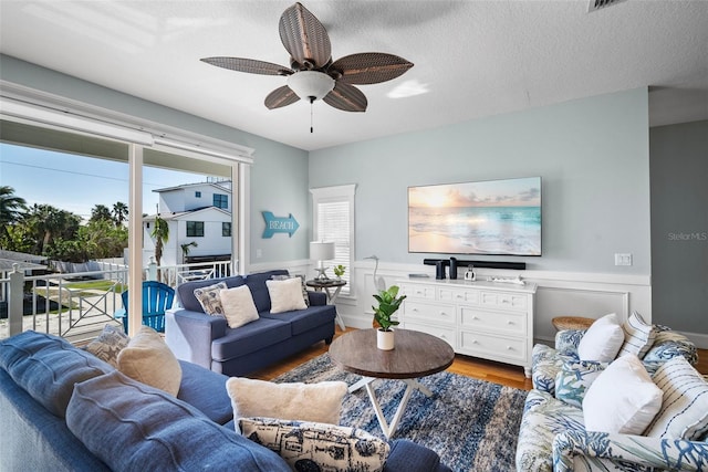 living room featuring ceiling fan, wood-type flooring, and a textured ceiling