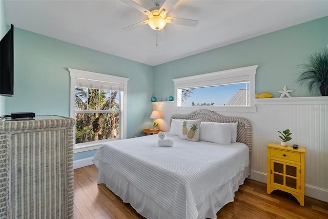 bedroom with multiple windows, wood-type flooring, and ceiling fan