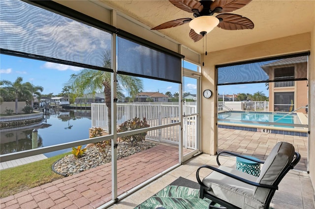 sunroom with ceiling fan and a water view